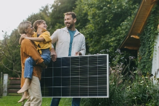 Familie vor Ihrem Eigenheim mit einem Solarpanel.